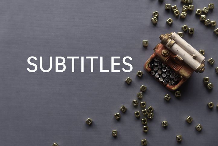 Top view of toys typewriter and gold alphabet beads on grey background written with Subtitles